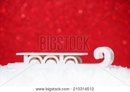 christmas card with old sleigh in snow, red background, copy space, bokeh