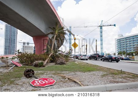 Miami Florida USA September 20 2017: Damaged trees and road sign stop on one of the streets. After hurricane Irma. Trash and damaged objects under the bridge.
