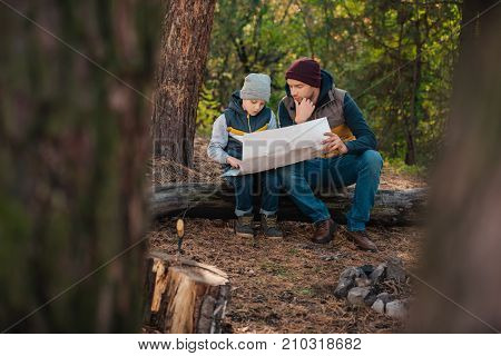Father And Son With Map In Forest