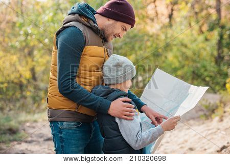 Father And Son With Map In Forest