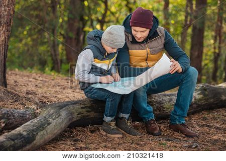 Father And Son With Map In Forest