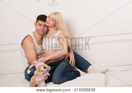 Beautiful pregnant couple in love on the background. Hands of husband on the tummy of his pregnant wife. Young man tenderly stroked pregnant belly of his wife. Husband kissing pregnant belly.