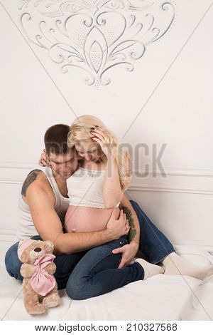 Beautiful pregnant couple in love on the background. Hands of husband on the tummy of his pregnant wife. Young man tenderly stroked pregnant belly of his wife. Husband kissing pregnant belly.
