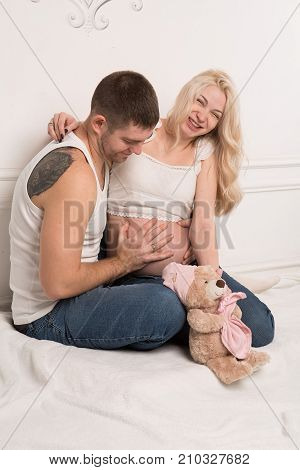 Beautiful pregnant couple in love on the background. Hands of husband on the tummy of his pregnant wife. Young man tenderly stroked pregnant belly of his wife. Husband kissing pregnant belly.