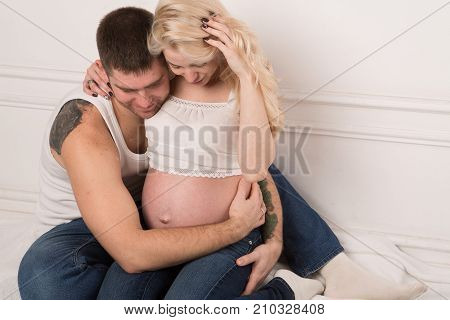 Beautiful pregnant couple in love on the background. Hands of husband on the tummy of his pregnant wife. Young man tenderly stroked pregnant belly of his wife. Husband kissing pregnant belly.