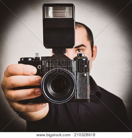 Professional photographer holding old retro film camera and flash. Portrait of working photographer with vintage camera fixed lens and on camera flash. Isolated on white background.