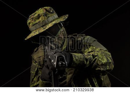 Portrait of armed woman with camouflage. Young female airsoft sniper observe with firearm. Soldier with gun in war black background. Military army people concept
