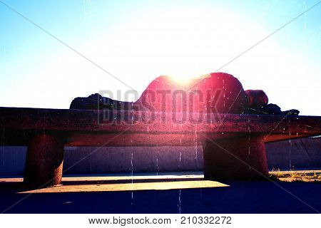 Flare soft focus. Silhouette in sunbath. Drank adult man rests on stony bench in park Sharp sun rays make contours around sleeping body.