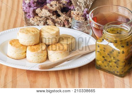 Homemade delicious plain scones with homemade passion fruit jam and tea in horizontal vintage tone style for background or wallpaper. Scones is English pastry for afternoon tea or coffee break. Scone and passion fruit jam served with tea.