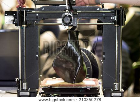 3D printer printing a model in the form of black vase close-up. The concept modern additive technology. The 4ht industrial revolution.