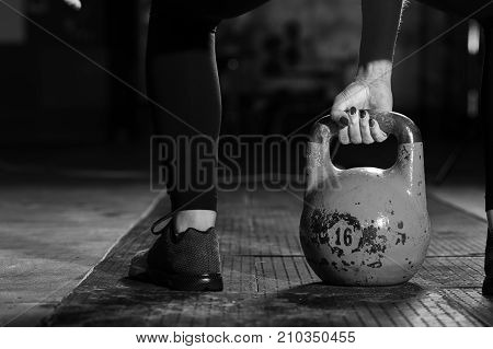 Cropped shot of female exercising with kettle bell. Young sporty woman practicing strength training in gym. Sports and fitness concept.