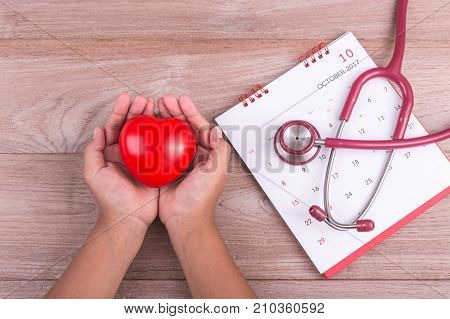 Check Heart Concept : Woman Hands Holding Red Heart And Stethoscope On Brown Wooden Table
