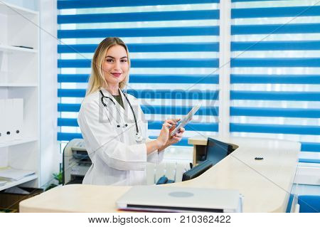 Young female receptionist holding tablet computer in hospital.