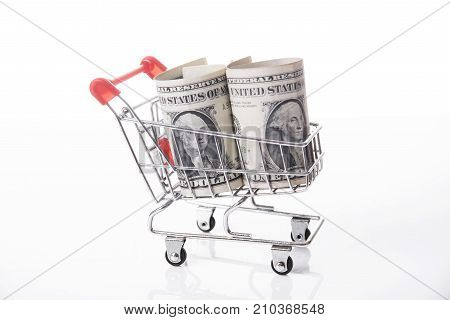 Shopping cart with dollar money isolated on white background.