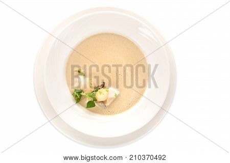 Top view of white ceramic plate with delicious creamy soup isolated on white.