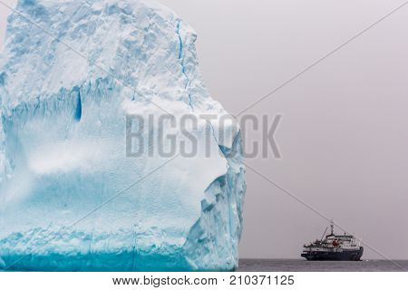 Huge piece of iceberg with antarctic cruise ship at the horizon Antarctica