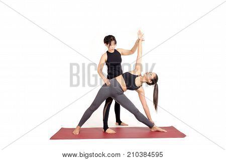 asian woman doing yoga training in Triangle pose on the mat with trainer teacher assists to make yoga pose isolated on white background exercise fitness sport training healthy lifestyle concept