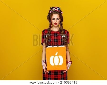 Colorful halloween. modern woman in Mexican style halloween costume on yellow background with shopping bag