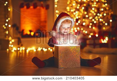 Merry Christmas!happy baby boy with magic gift at home near Christmas tree and fireplace