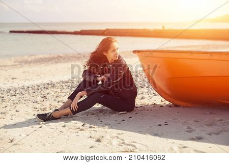 A Girl Sideways Near A Red Boat On The Beach By The Sea
