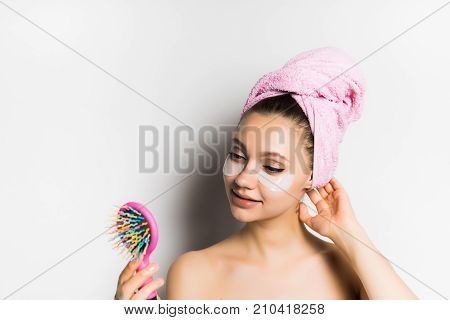 young beautiful girl with clean skin and with a pink towel smiling and looking in the mirror