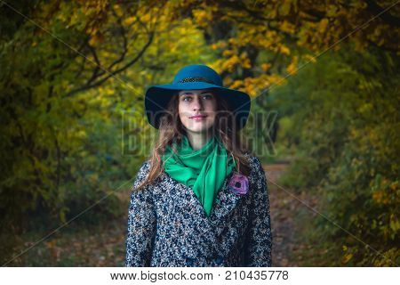 Pretty romantic girl in autumn clothes walks in a park. The mood of autumn leaf fall. Autumn fashion.
