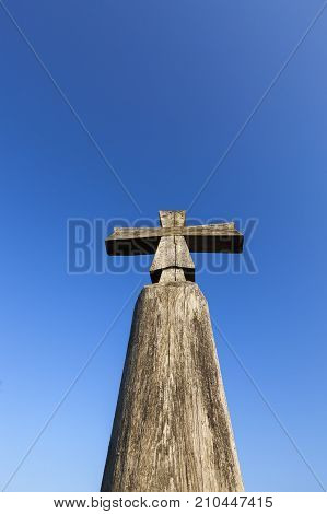 Old Wooden Christian Cross On A Background Of Blue Sky. Close-up Photo