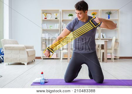 Young man exercising at home in sports and healthy lifestyle concept