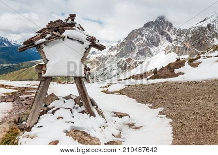snow covered cairn with distance marker at Forca Rossa mountain pass in Dolomites, Italy