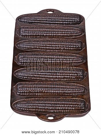 Old but seasoned cast-iron pan ready for baking cornbread sticks in the shape of corn on the cob isolated against a white background vertical
