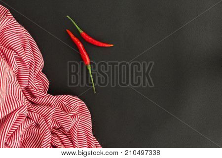 Red chili peppers and striped towel on black background. Asian food concent.
