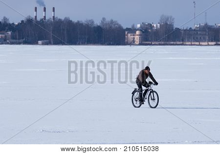 The lake Sestroretsky Razliv St.Petersburg (Russia) - March 14 2017: Unidentified male cyclist riding a bike in the winter on the frozen lake