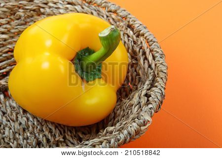 Beautiful of sweet yellow bell pepper isolated in basket on orange background.