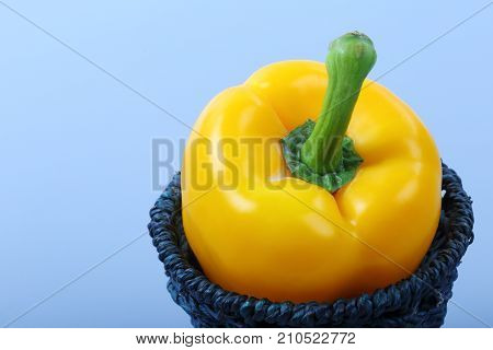 Close up of sweet yellow bell pepper isolated in basket on blue background.