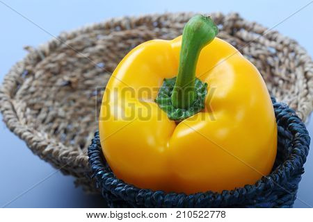 Close up of sweet yellow bell pepper isolated in basket on blue background.
