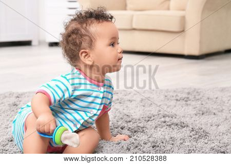 Cute little African American baby with nibbler on carpet