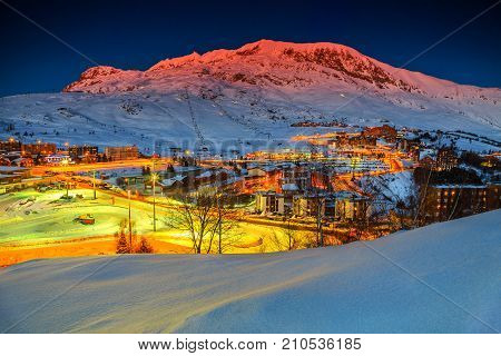 Stunning winter sunset landscape and ski resort with typical alpine wooden houses in French Alps, Alpe D Huez, France, Europe