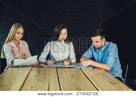 Young team of coworkers watching storyboard for shooting video in modern coworking office. Teamwork process. Horizontalblurred background.