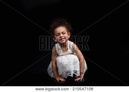 Kid Sitting On Hunkers In White Dress