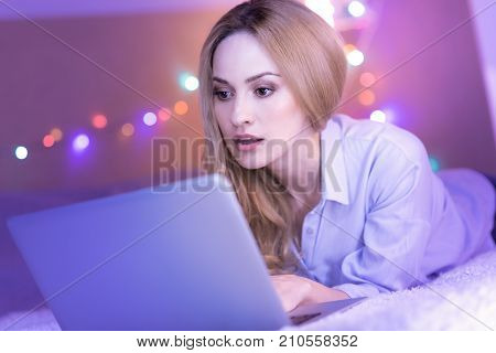 I cant believe. Attractive surprised young woman looking baffled and while working on her laptop and watching at it