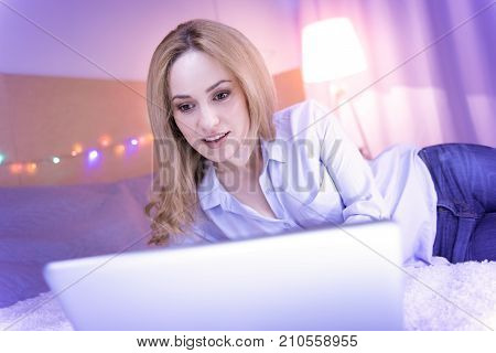 Freelancing. Attractive dark-eyed young woman smiling and feeling happy while working on her laptop