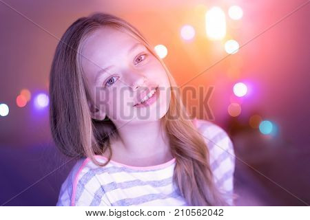 Emotting happiness. Cheerful blond blue-eyed girl smiling and looking straight into the cam and her eyes shining