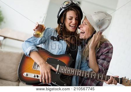 Young beautiful happy dancing girls playing guitar and partying