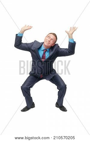 A young business man stands on bent knees and holds his hands above his head as if he is carrying something or holding it isolated on white background.