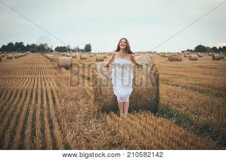 Beautiful Girl Running In The Field With A Bales Of Hay