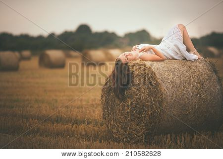 Beautiful Girl Lying On A Bale Of Hay In The Field