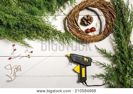Make a Christmas wreath with your own hands. Spruce branch, Christmas wreath and gifts on a white wooden background. Workplace for preparing handmade decorations. Christmas and New year