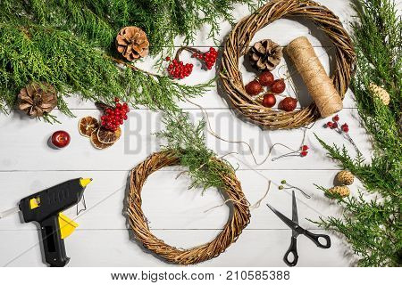 Make a Christmas wreath with your own hands. Spruce branch, Christmas wreath and gifts on a white wooden background. Workplace for preparing handmade decorations. Christmas and New year