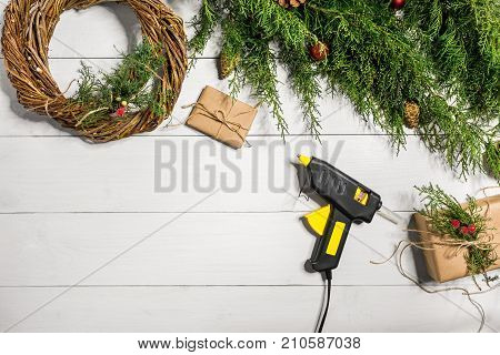 Make a Christmas wreath with your own hands. Spruce branch, Christmas wreath and gifts on a white wooden background. Workplace for preparing handmade decorations. Christmas and New year