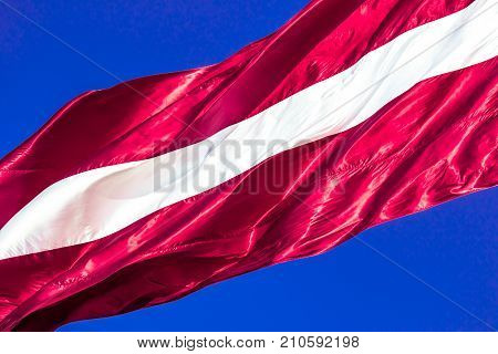 Silky flag of Latvia flying on a cler blue sky